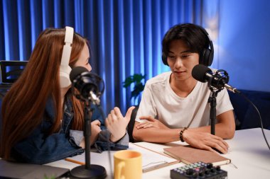 Genç adam ve kadın küçük yayın stüdyosunda mikrofon ve dizüstü bilgisayar kullanarak canlı yayın yapan radyo yayını için röportaj yapacaklar.,