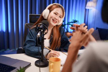 Genç adam ve kadın küçük yayın stüdyosunda mikrofon ve dizüstü bilgisayar kullanarak canlı yayın yapan radyo yayını için röportaj yapacaklar.,