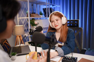 Genç adam ve kadın küçük yayın stüdyosunda mikrofon ve dizüstü bilgisayar kullanarak canlı yayın yapan radyo yayını için röportaj yapacaklar.,