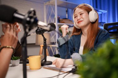 Genç adam ve kadın küçük yayın stüdyosunda mikrofon ve dizüstü bilgisayar kullanarak canlı yayın yapan radyo yayını için röportaj yapacaklar.,