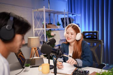 Genç adam ve kadın küçük yayın stüdyosunda mikrofon ve dizüstü bilgisayar kullanarak canlı yayın yapan radyo yayını için röportaj yapacaklar.,