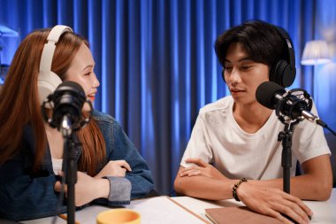 Genç adam ve kadın küçük yayın stüdyosunda mikrofon ve dizüstü bilgisayar kullanarak canlı yayın yapan radyo yayını için röportaj yapacaklar.,