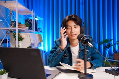 İyi ışıklandırılmış bir stüdyoda podcast kaydı sırasında anlamlı el hareketleri kullanan içerik yaratıcısı.