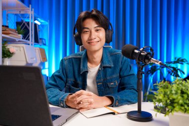 Profesyonel stüdyo ortamında podcast yapan adam. Canlı yayına mikrofon ve kulaklıkla bağlanıyoruz. Podcast ve çevrimiçi yayın kavramı.