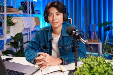 Profesyonel stüdyo ortamında podcast yapan adam. Canlı yayına mikrofon ve kulaklıkla bağlanıyoruz. Podcast ve çevrimiçi yayın kavramı.