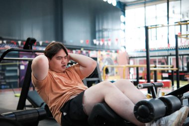 Spor salonunda abdominal egzersiz makinesinde egzersiz yapan kilolu bir adam. Çekirdek gücü ve kilo kaybı. Konsept kararlılık, fitness yolculuğu.