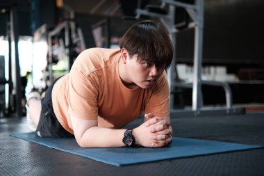 Mat Spor Salonunda Kalas Egzersizi Yapan Kilolu Adam. Çekirdek Kuvveti ve Dayanıklılık Eğitimi