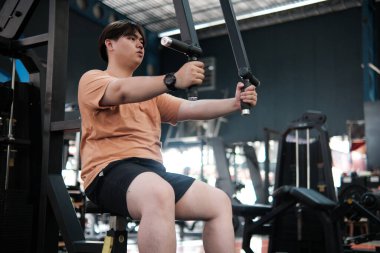 Spor salonunda Şişman Adam Göğüs Sineği Makinesi Kullanıyor. Kuvvet ve Zindelik Eğitimi