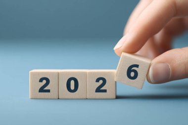 Hand is holding wooden blocks that spell out the year 2026. The blocks are stacked on top of each other, with the number 2 on the bottom block. Concept of nostalgia and the passing of time