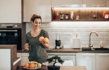 Shot of a happy young woman preparing a breakfast of fruit in her kitchen at home.