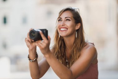 Yabancı bir şehri keşfederken gülümseyen genç bir kadının fotoğrafı..