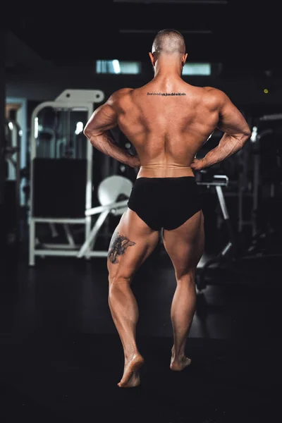 一名年轻的健美健美运动员在健身房锻炼后的后视镜显示出他完美的背部肌肉 — 图库照片