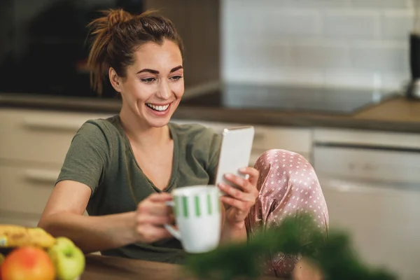 Snímek Mladé Ženy Pomocí Svého Smartphonu Při Pití Kávy Doma — Stock fotografie