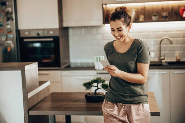 Jonge Glimlachende Vrouw Met Behulp Van Haar Smartphone Ochtend Thuis — Stockfoto