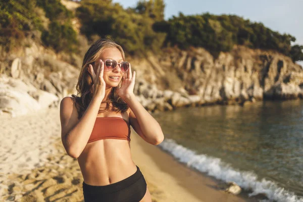 ハート型のサングラスをかけたかわいい笑顔のティーンの女の子がビーチで夏休みを楽しんでいます — ストック写真