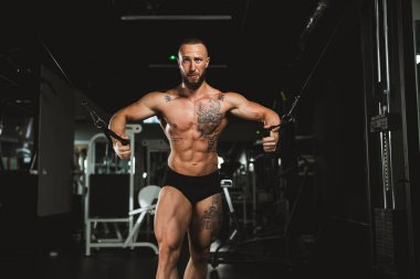 Genç kaslı bir vücut geliştirici spor salonunda göğüs kasları için sıkı antrenman yapıyor..