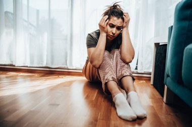 Depresyondaki yalnız genç kadın pencerenin kenarında oturur ve kötü karamsar düşüncelerde kaybolur..