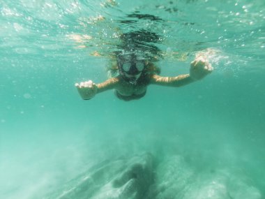Güzel bir genç kadın yaz tatilinde deniz tabanını keşfederken denizde dalgıçlık yaparken eğleniyor..