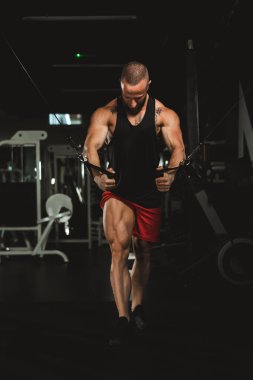 Genç kaslı bir vücut geliştirici spor salonunda göğüs kasları için sıkı antrenman yapıyor..