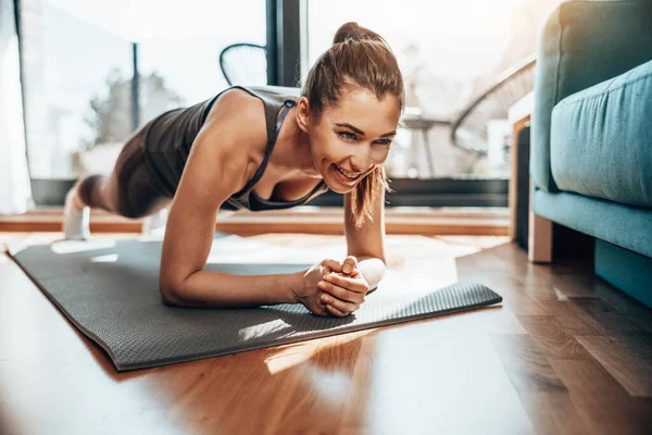 stock image Young woman doing plank exercises during training in the living room at home.