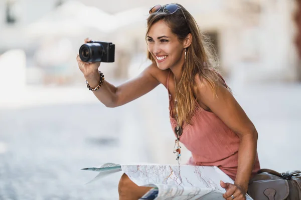 拍了一个年轻的微笑的女人在探索外国城市的时候拍照 — 图库照片