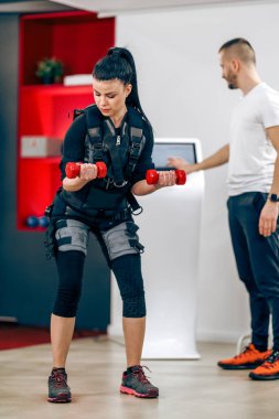 Young woman is doing EMS personal training with coach in the gym.