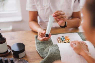 Manikür tedavisi sırasında müşteriye el nemlendirici krem gösteren tanınmayan bir güzellik uzmanına yaklaş..