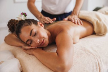 Genç bir kadın güzellik salonundaki bir profesyonelden yosun çamuru tedavisi görüyor..