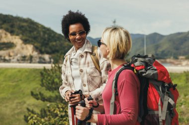 Dağda yürüyüş yaparken sırt çantalı iki bayan arkadaş konuşuyor..