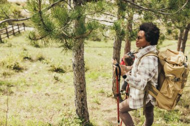 Güneşli bir sonbahar gününde sırt çantasıyla dağlarda yürüyüş yapan olgun siyahi bir kadın..