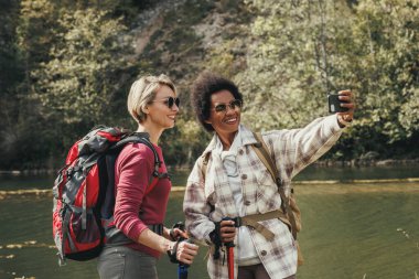 Dağda yürüyüş yaparken nehirde selfie çeken iki melez kız arkadaş..