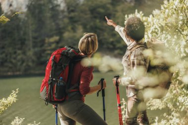 İki bayan arkadaş ormanda yürüyüşlerinin bir kısmında bir nehrin kenarında mola verir..