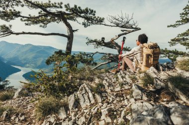Yetişkin siyah kadın dağ yamacında otururken manzaranın tadını çıkarıyor..