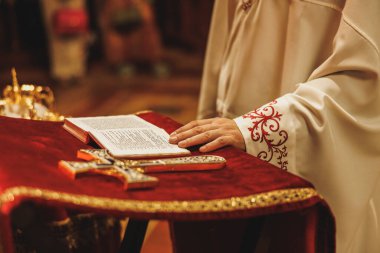 Ortodoks Hıristiyan kilisesinde bir rahibin eli ve üzerinde İncil olan bir masa..