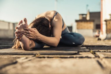 Rahat bir kadın terasta yoga egzersizi yapıyor..