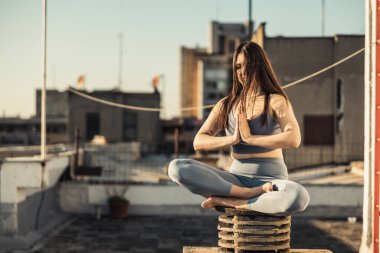 Rahat bir kadın terasta yoga egzersizi yapıyor..