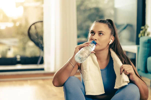 Genç bayan su içiyor ve evde eğitime hazırlanıyor..