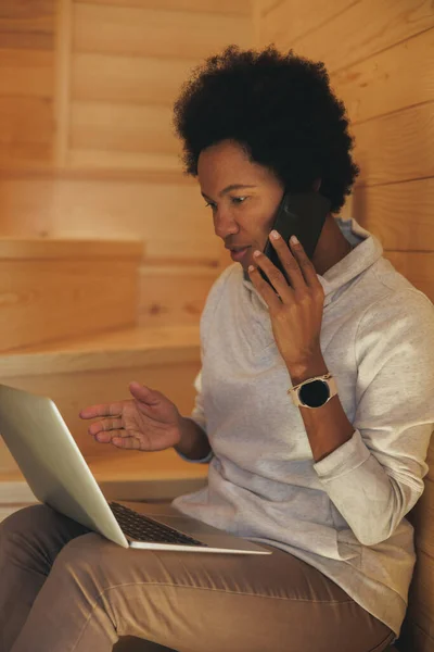 Černá Žena Mluví Smartphone Při Použití Notebooku Během Dovolené Útulném — Stock fotografie