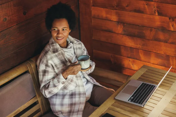Svart Kvinna Dricker Morgonkaffe Och Använder Laptop Medan Tillbringar Semestern — Stockfoto