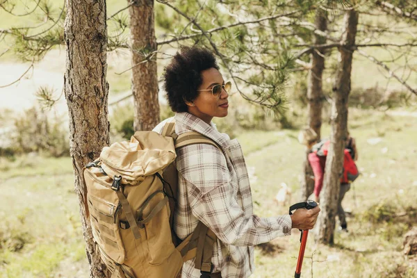 Güneşli bir sonbahar gününde sırt çantasıyla dağlarda yürüyüş yapan olgun siyahi bir kadın..