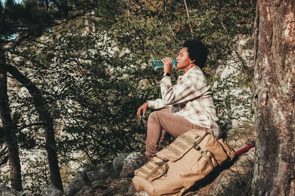 山のハイキング中に水休憩を取る成熟した黒人女性 — ストック写真