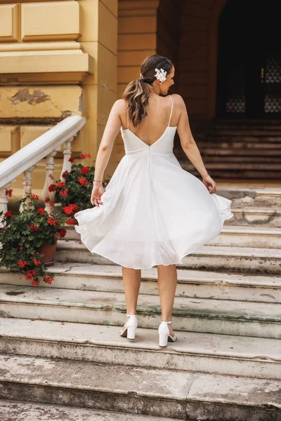 一个穿着漂亮的白色婚纱的漂亮新娘在婚礼当天在户外欢快跳舞的背影 — 图库照片