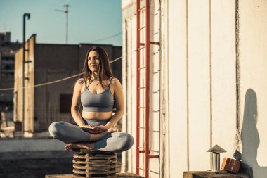 Relaxed woman practicing yoga meditating on a rooftop terrace.
