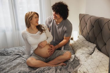 Mutlu hamile çift yatak odasında bir yatakta dinleniyor.. 