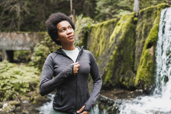 自然の中で山の滝の近くにジョギングする前にリラックスした成熟したアフリカ系アメリカ人女性 — ストック写真