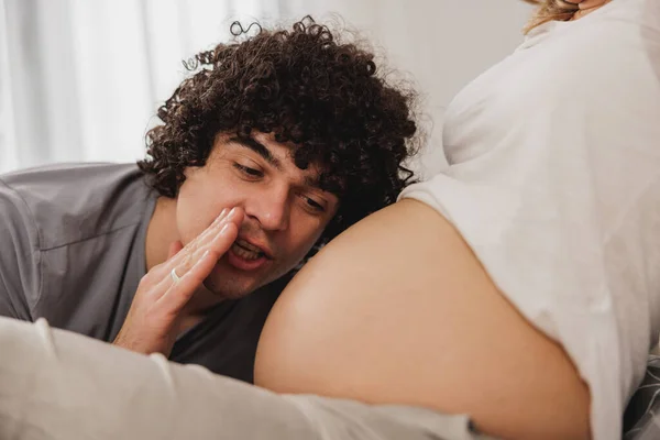 幸せな妊娠中のカップル楽しいを持っていると自宅で妊娠中のお母さんの胃の中に期待赤ちゃんと通信 — ストック写真