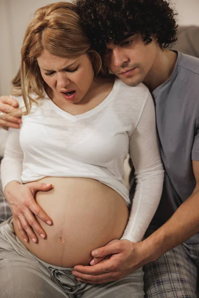Zaniepokojony Mężczyzna Pociesza Swoją Ciężarną Żonę Sypialni Która Skurcze Prenatalne — Zdjęcie stockowe