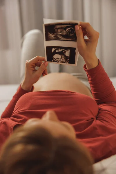 ベッドルームのベッドでリラックスしながら赤ちゃんの超音波を見てリラックスした若い未来の母親 — ストック写真