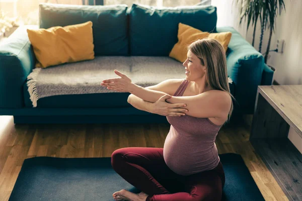 自宅でヨガをしている妊婦さん 彼女はリビングルームでストレッチトレーニングをしている — ストック写真