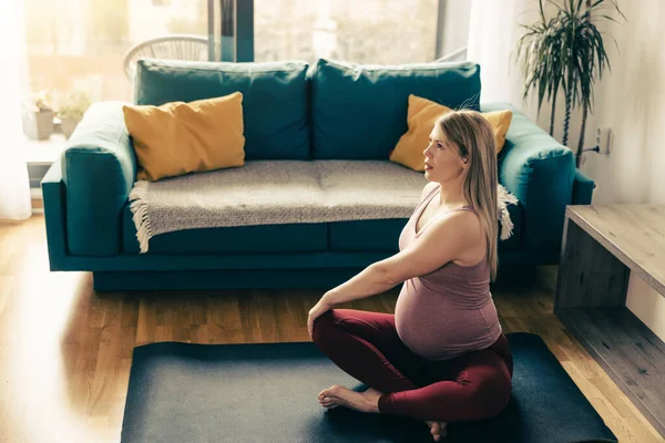 年轻的孕妇在家里锻炼 她在运动垫上锻炼 在客厅里舒展筋骨 — 图库照片